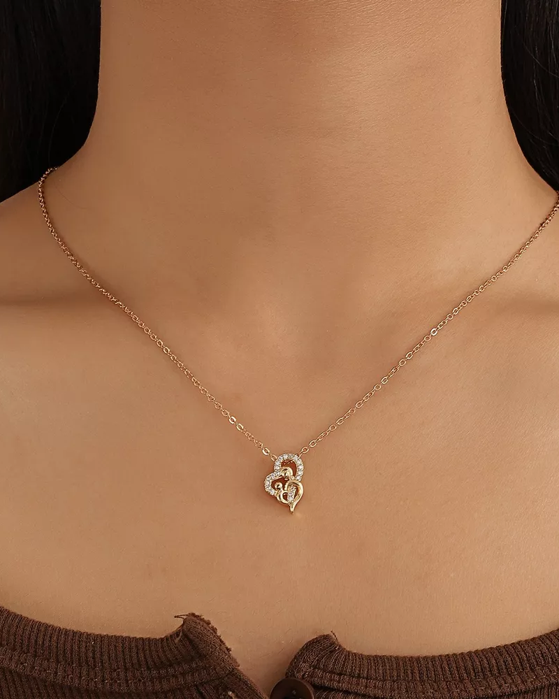Gold necklace with a heart-shaped pendant on a model against a dark background