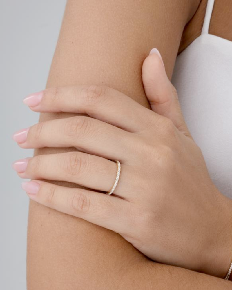 Model wearing ultra-thin gold stackable ring on ring finger