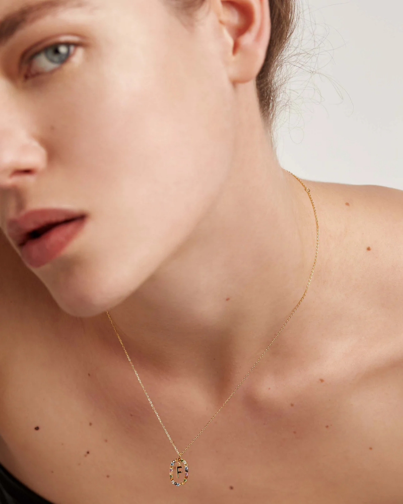 Close-up of a woman wearing a delicate gold necklace with a small pendant.