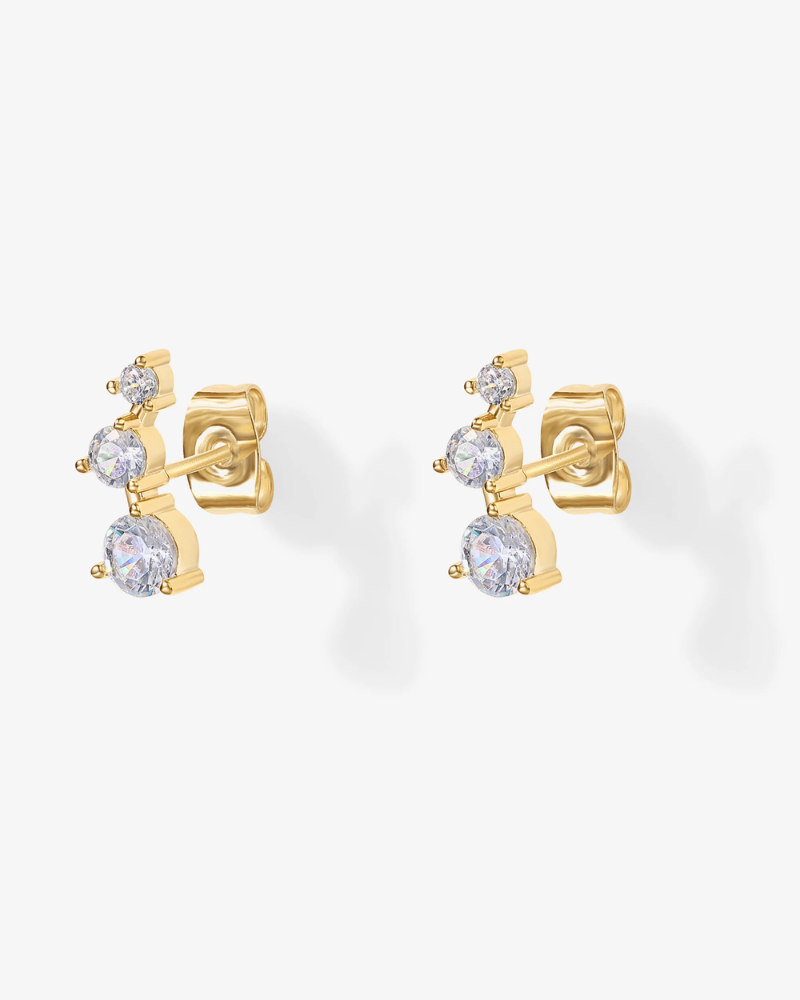 Gold earrings with clear gemstones on a white background