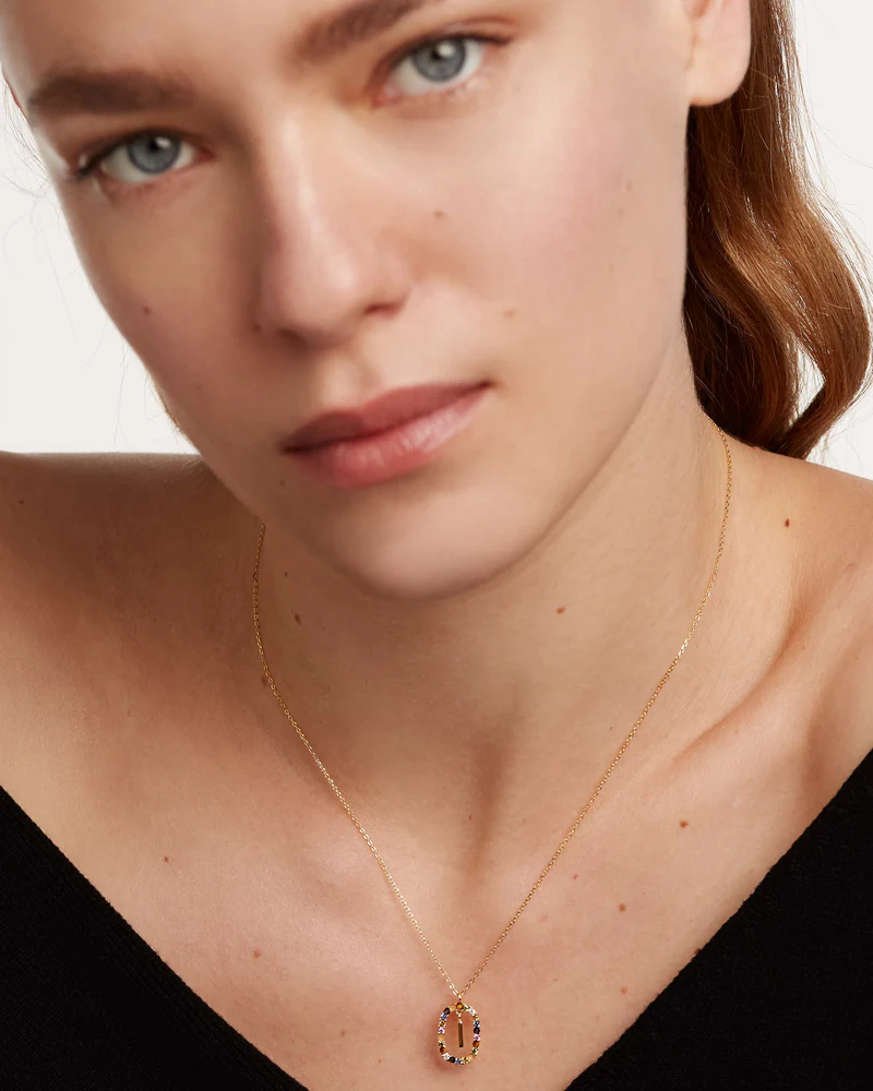 Close-up of a person wearing a delicate gold necklace with a pendant.