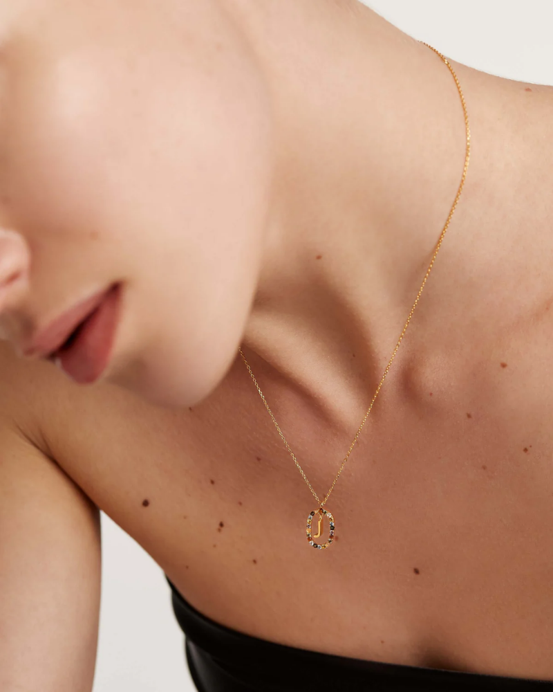 Gold necklace with a pendant worn by a person on a neutral background