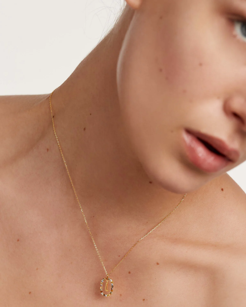 Close-up of a person wearing a gold necklace with a pendant.