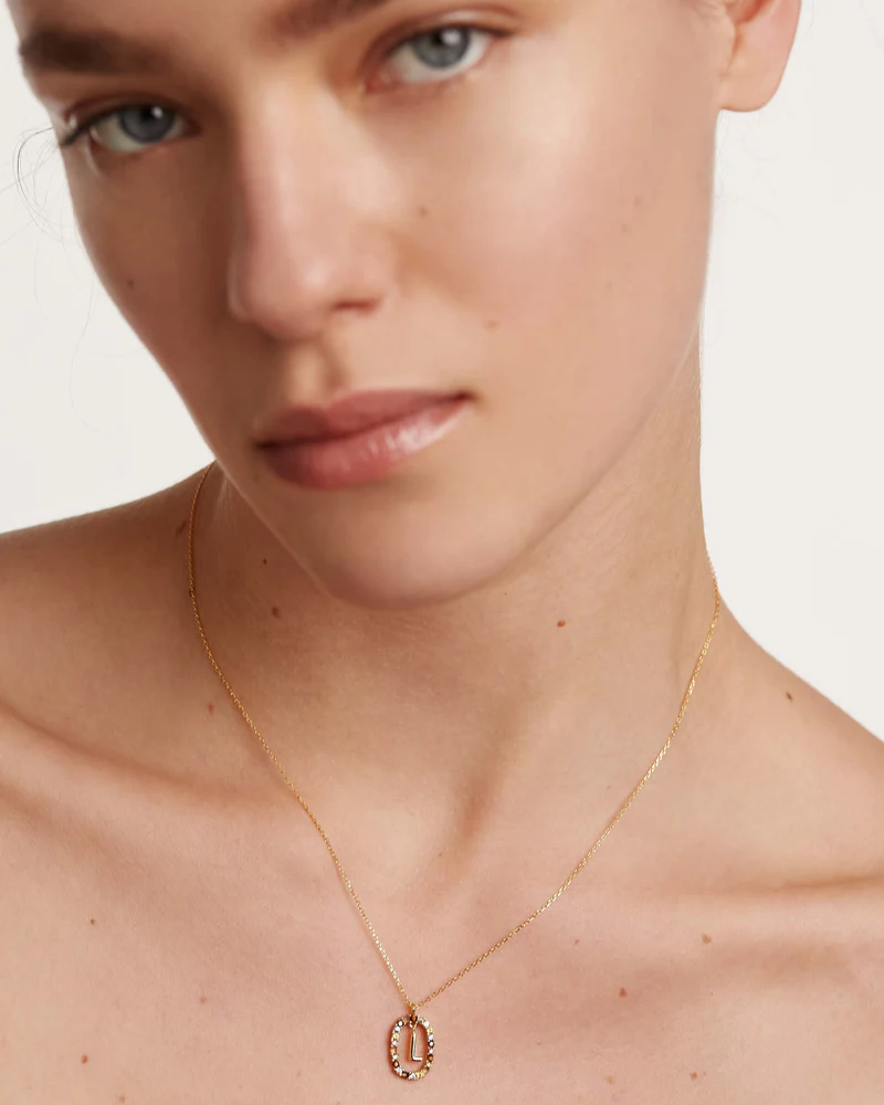 Close-up of a person wearing a gold necklace with a pendant on a plain background