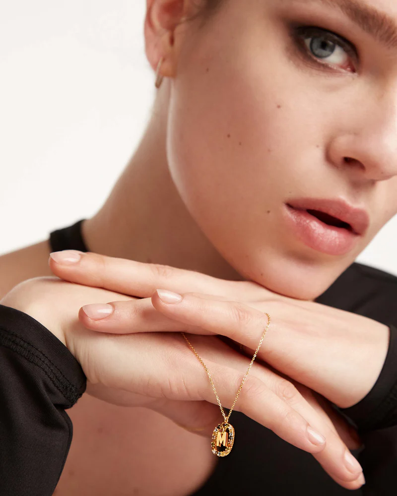 Close-up of a person wearing a gold necklace with a pendant.