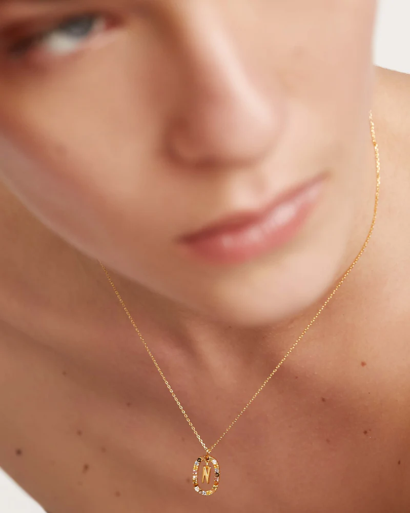 Close-up of a person wearing a gold necklace with a pendant.