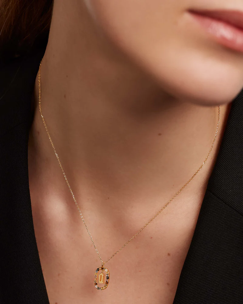 Gold necklace with a pendant on a person wearing a black outfit