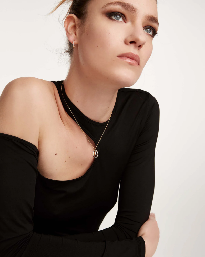 Woman wearing a black off-shoulder top with a plain background
