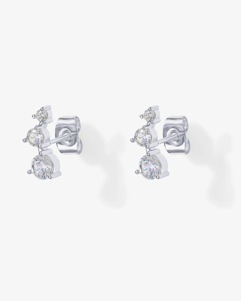Pair of silver earrings with clear gemstones on a white background