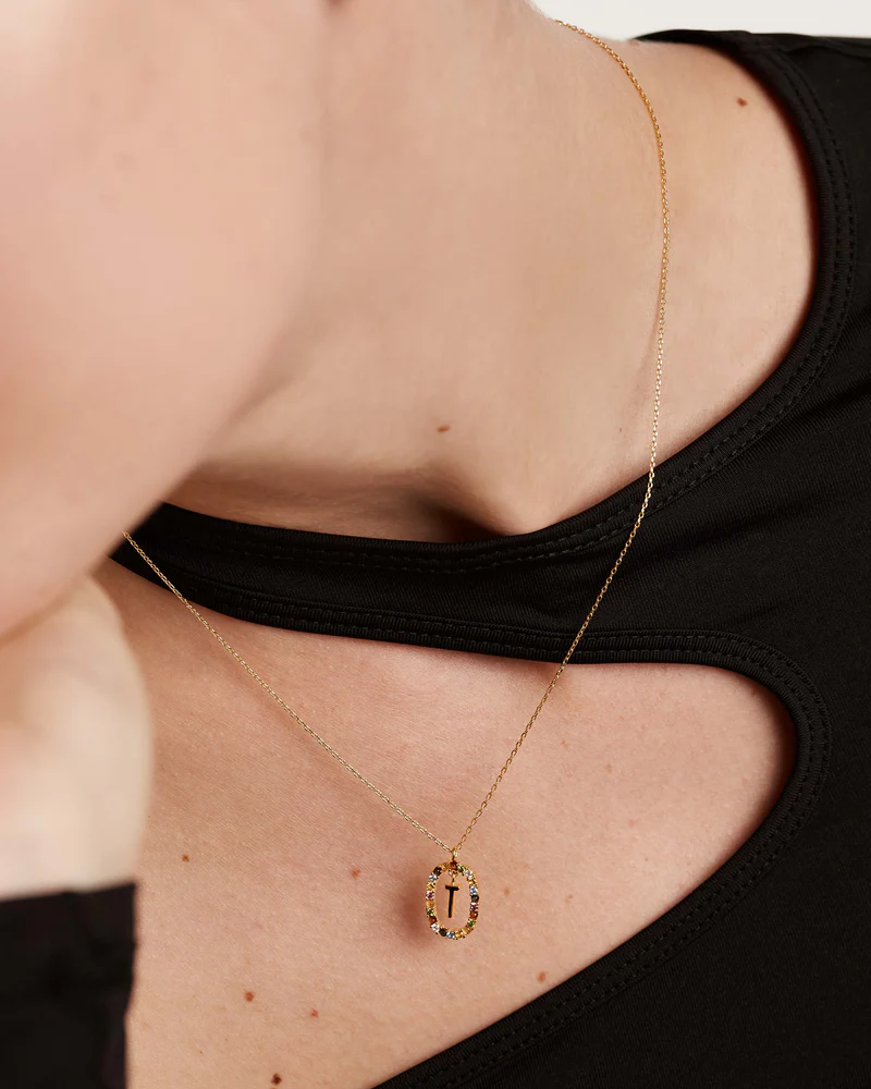 Gold necklace with a pendant worn by a person in a black top.