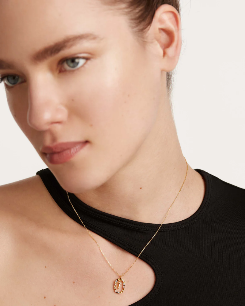Close-up of a person wearing a gold necklace with a pendant on a plain background