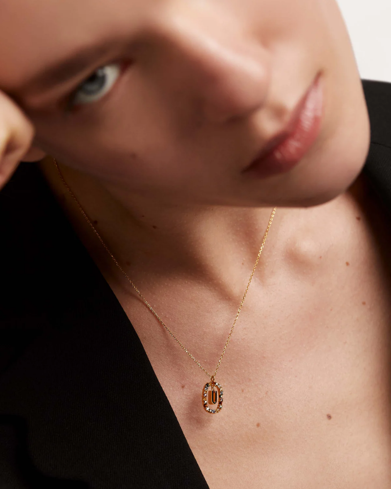 Close-up of a person wearing a gold necklace with a pendant.