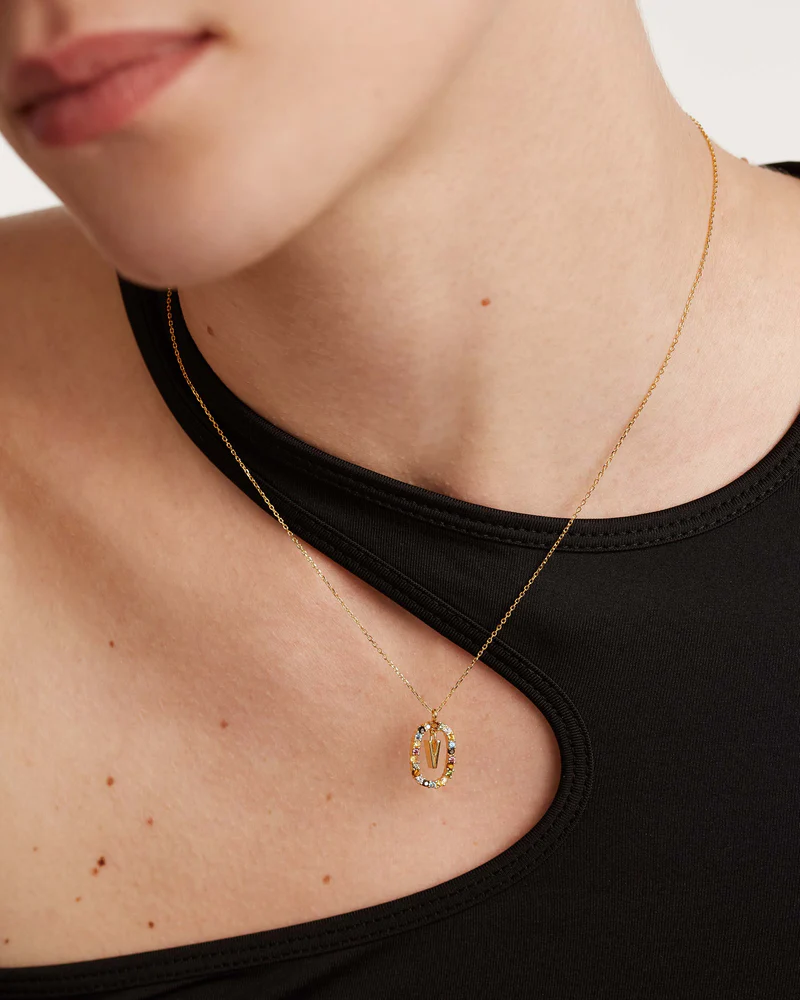 Gold necklace with a pendant worn by a person in a black top.