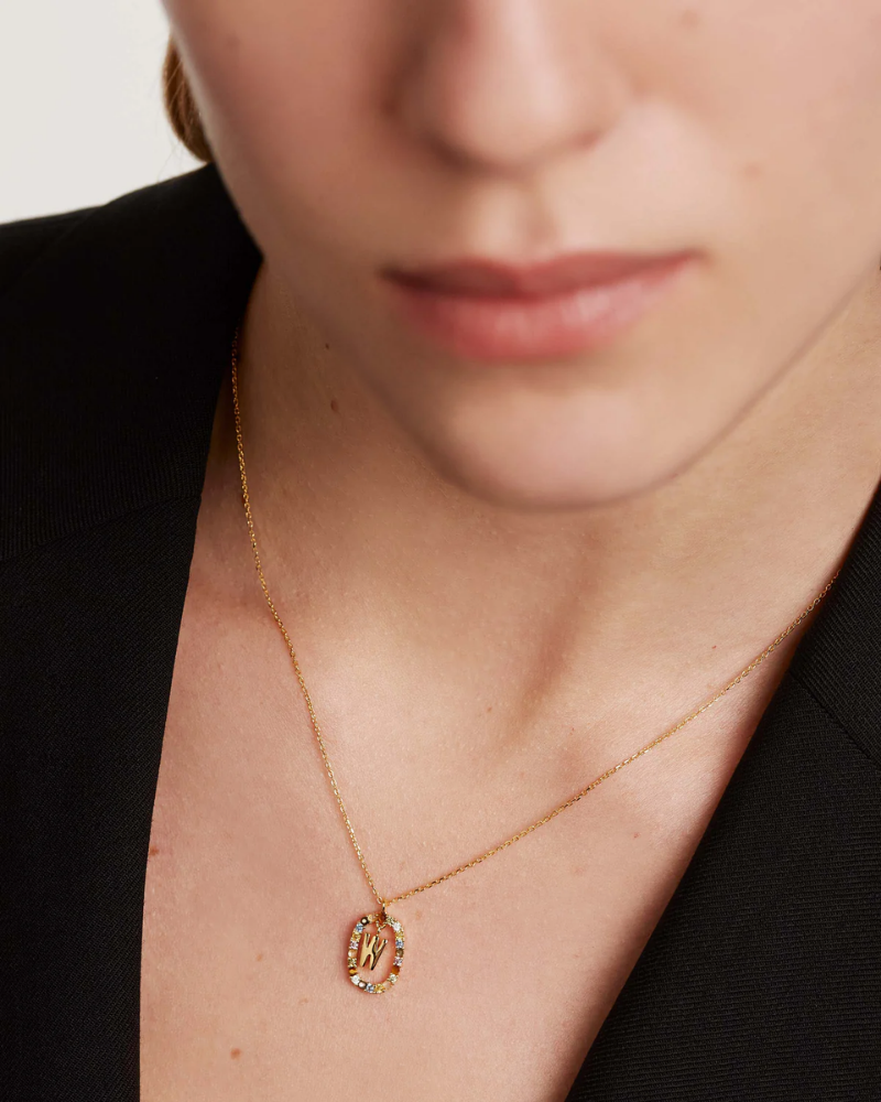 Close-up of a person wearing a gold necklace with a pendant.