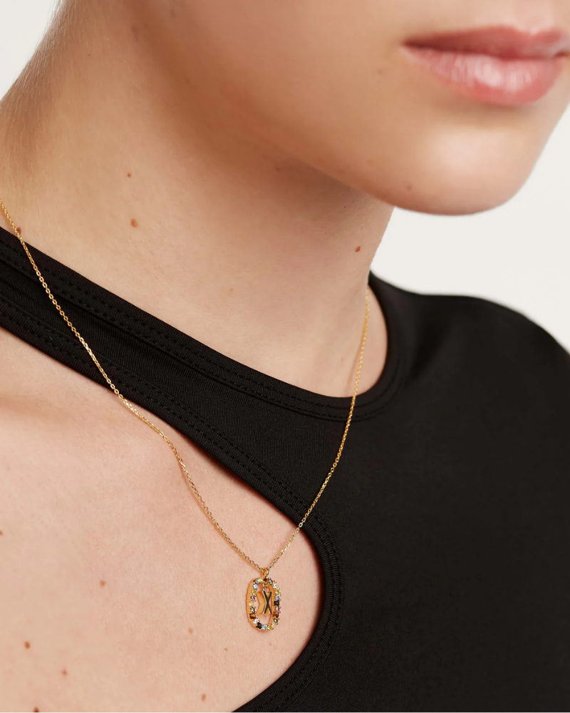 Gold necklace with a pendant worn by a person against a neutral background