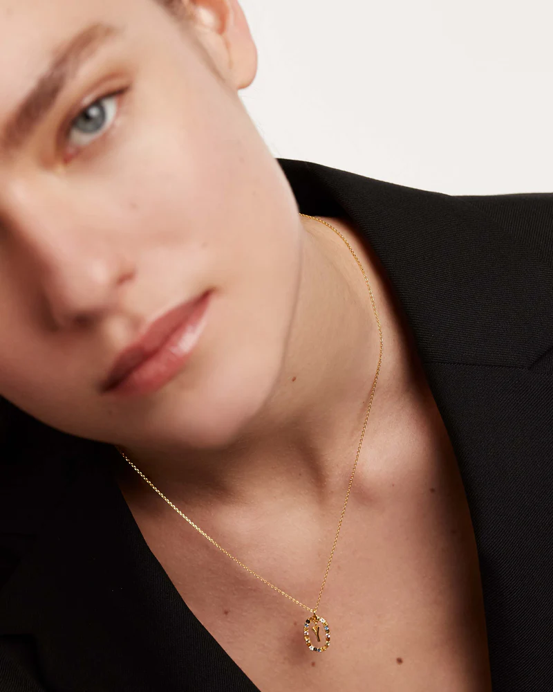 Close-up of a person wearing a gold necklace with a pendant.